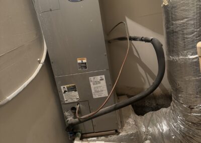 Carrier HVAC unit in a basement with ductwork and pipes. Image is rotated.