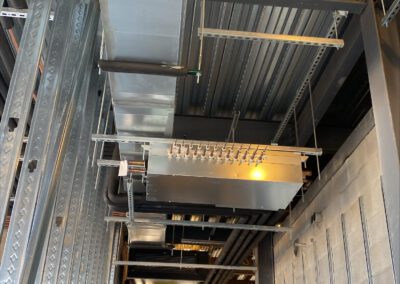 Interior of a building under construction with exposed ductwork, a worker on a scissor lift, and metal framing.